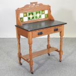 An Edwardian satin walnut washstand, with a marble top and a tiled galley back,