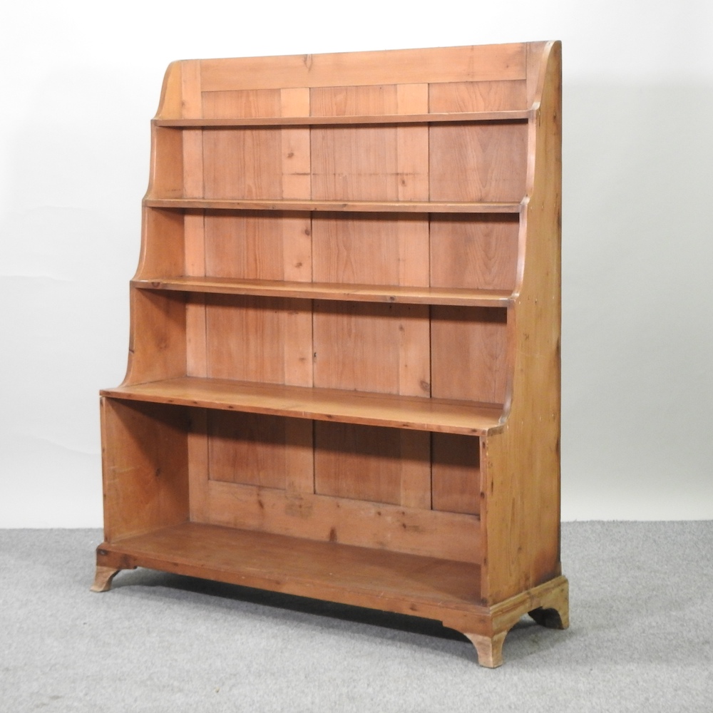 An antique pine waterfall bookcase, on swept bracket feet,