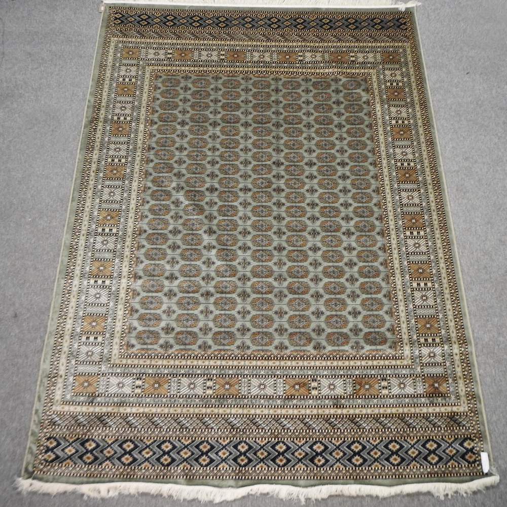 A Bokhara style carpet, with geometric design on green ground,