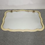 A cream painted cartouche shaped wall mirror, with gilt decoration,