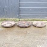 A cast iron circular pig feeder, together with two others,