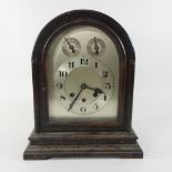 A mahogany cased mantel clock, with an arched top and silvered dial,