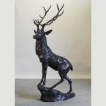 A life-size bronze model of a stag, standing on a rocky base,