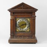 An oak cased mantel clock, with a brass dial,