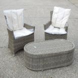A beige rattan armchair, together with another, with cushions, and an oval coffee table,