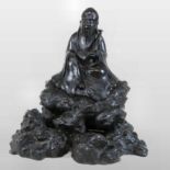 A Chinese bronze figure of a man, seated holding a sceptre, on a rocky base,