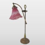 A French brass adjustable table light, with an opaque red frilled glass shade, signed Daum Nancy,