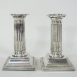 A pair of Edwardian silver table candlesticks, each in the form of a Corinthian column,