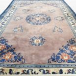 A large Chinese woollen carpet, the central medallion on a pink ground, within multiple borders,