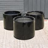 A set of three circular black garden pots,