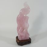 A Chinese carved rose quartz figure of a deity, on a hardwood stand,