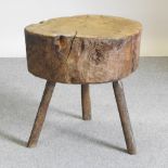 A large rustic occasional table, made from a tree trunk, on splayed legs,