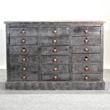 A dark grey painted apothecary style chest, containing three rows of six short drawers,