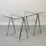 A contemporary side table with a glass top on chrome supports,