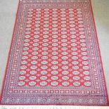 A Bokhara style carpet, on a red ground,