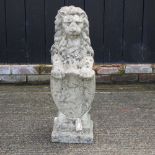 A reconstituted stone garden model of a lion, resting on a shield,