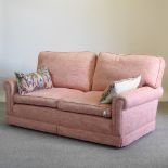 A hand made pink upholstered sofa, with loose cushions,