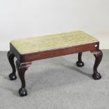 An Edwardian mahogany upholstered footstool, on claw and ball feet,