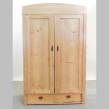 An antique pine double wardrobe, with drawer below,