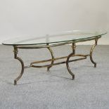 A brass coffee table, of oval shape, with a glass top,