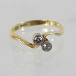 An 18 carat gold two stone diamond ring, of crossover design,
