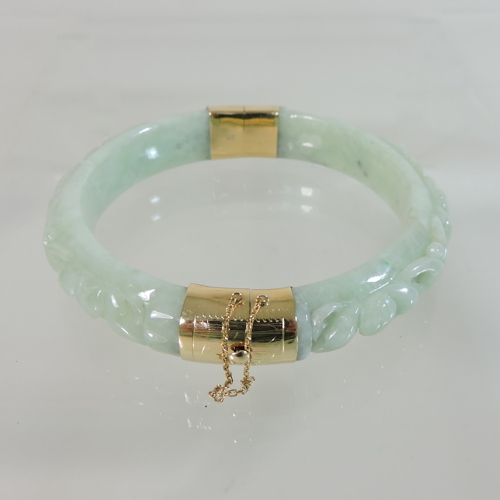 A 14 carat gold mounted carved jade bangle,