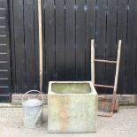 A galvanised water tank, together with a wooden pitchfork,