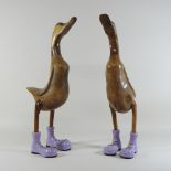 A pair of large wooden ducks, wearing purple boots,