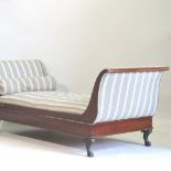 An Empire style parcel gilt day bed, upholstered in grey striped fabric, on ebonised carved feet,