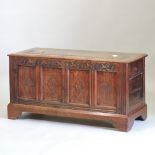 An 18th century and later carved oak coffer, with a hinged top and panelled front,
