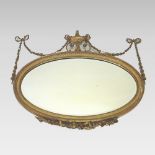 A late Victorian gilt gesso framed wall mirror, of oval shape,