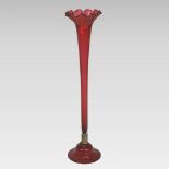 A large Victorian floor standing cranberry glass lily vase, of slender tapered shape,