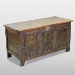 An 18th century carved oak coffer, with a hinged lid and panelled front,
