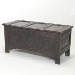 An 18th century carved oak coffer, with a hinged lid and panelled front,