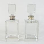 A pair of modern silver mounted glass decanters and stoppers, each of plain square shape,
