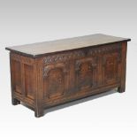 An 18th century carved oak and inlaid coffer, with a hinged lid and arched panelled front,