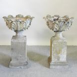 A pair of reconstituted stone garden urns, each on a pedestal base,