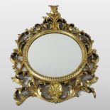 An ornate 19th century carved pine and gilt gesso framed wall mirror, of circular shape,