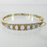 A 9 carat gold opal and diamond set bangle, of hinged design,