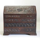 A 19th century heavily carved dark oak bureau, with a fitted interior, on bracket feet,