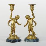 A pair of continental gilt figural table candlesticks, each with a cherub support, on a marble base,