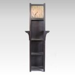 An Arts and Crafts style oak clock/bookcase, having a brass dial, with open shelves,