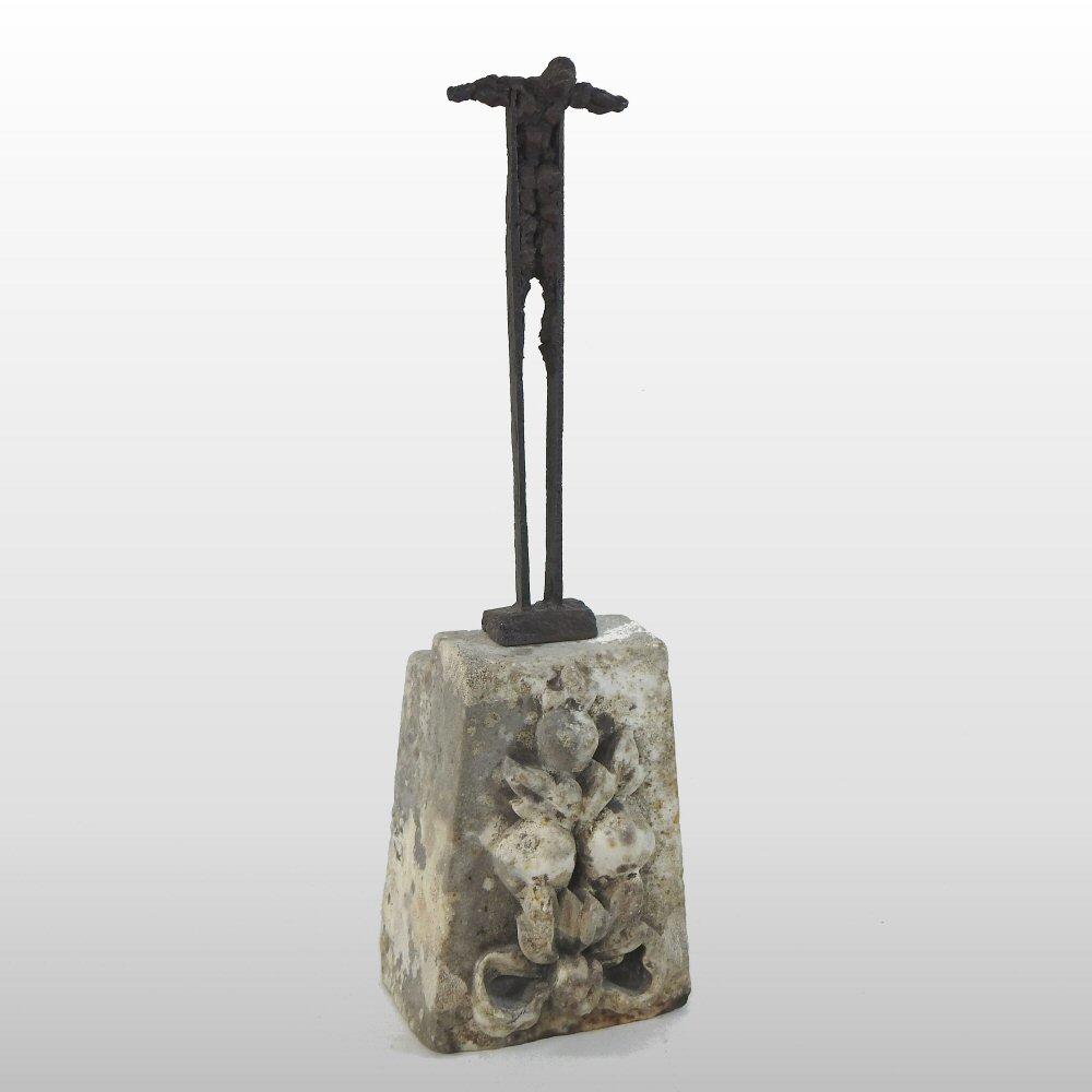 A contemporary iron sculpture, crucifixion, on a marble keystone,