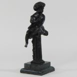 A bronze figure of a boy seated on a column, mounted on a marble base,