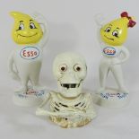 A skeleton money box, together with a pair of esso painted metal money banks,