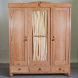 A continental antique pine triple wardrobe, with drawers below,