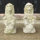 A pair of reconstituted stone gatepost markers, each in the form of a lion holding a shield,