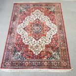 A woollen Heriz style carpet, with a central medallion and floral designs on a red ground,