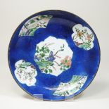An 18th century Japanese blue glazed dish, reserved with floral panels, on a mottled blue ground,