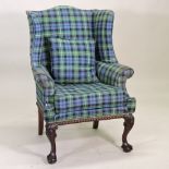 A George I style carved mahogany wing armchair, upholstered in tartan,